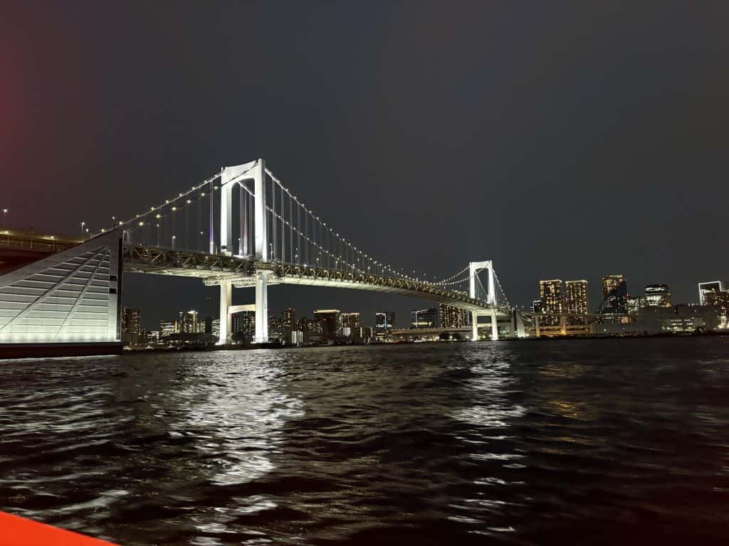 A photo of a brightly lit bridge as we pass under with a boat.